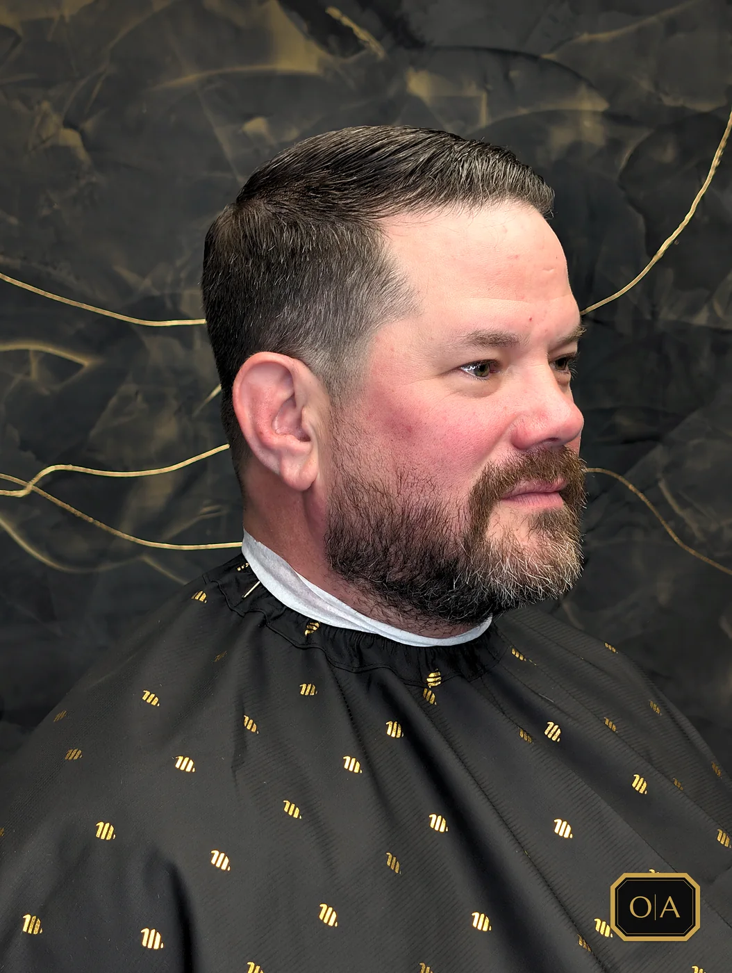 A finished short taper with a side part, seen from the side against the shop's black wall