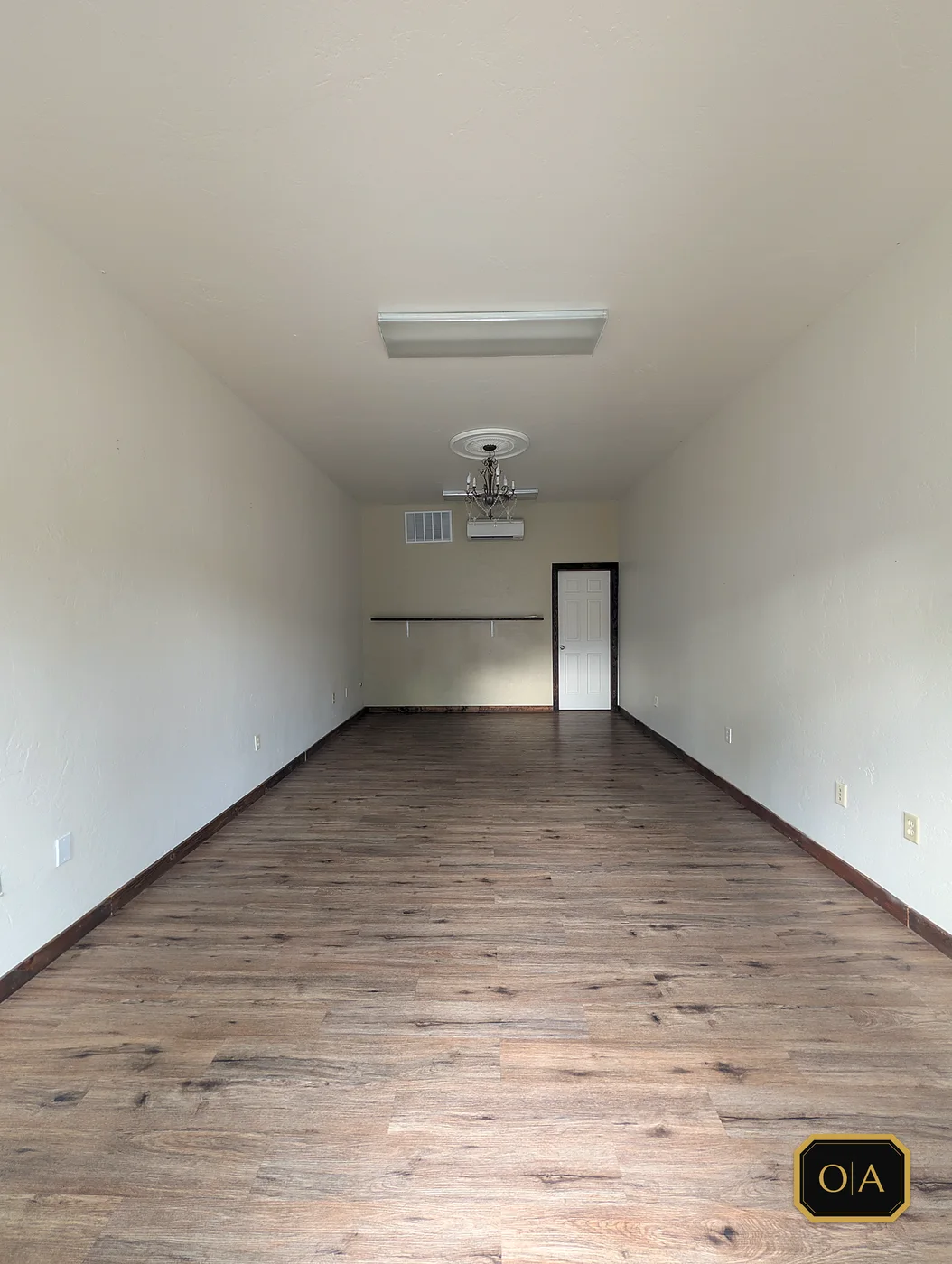 The unit as handed over: bare cream walls, a chandelier and the existing floor, before any work started.