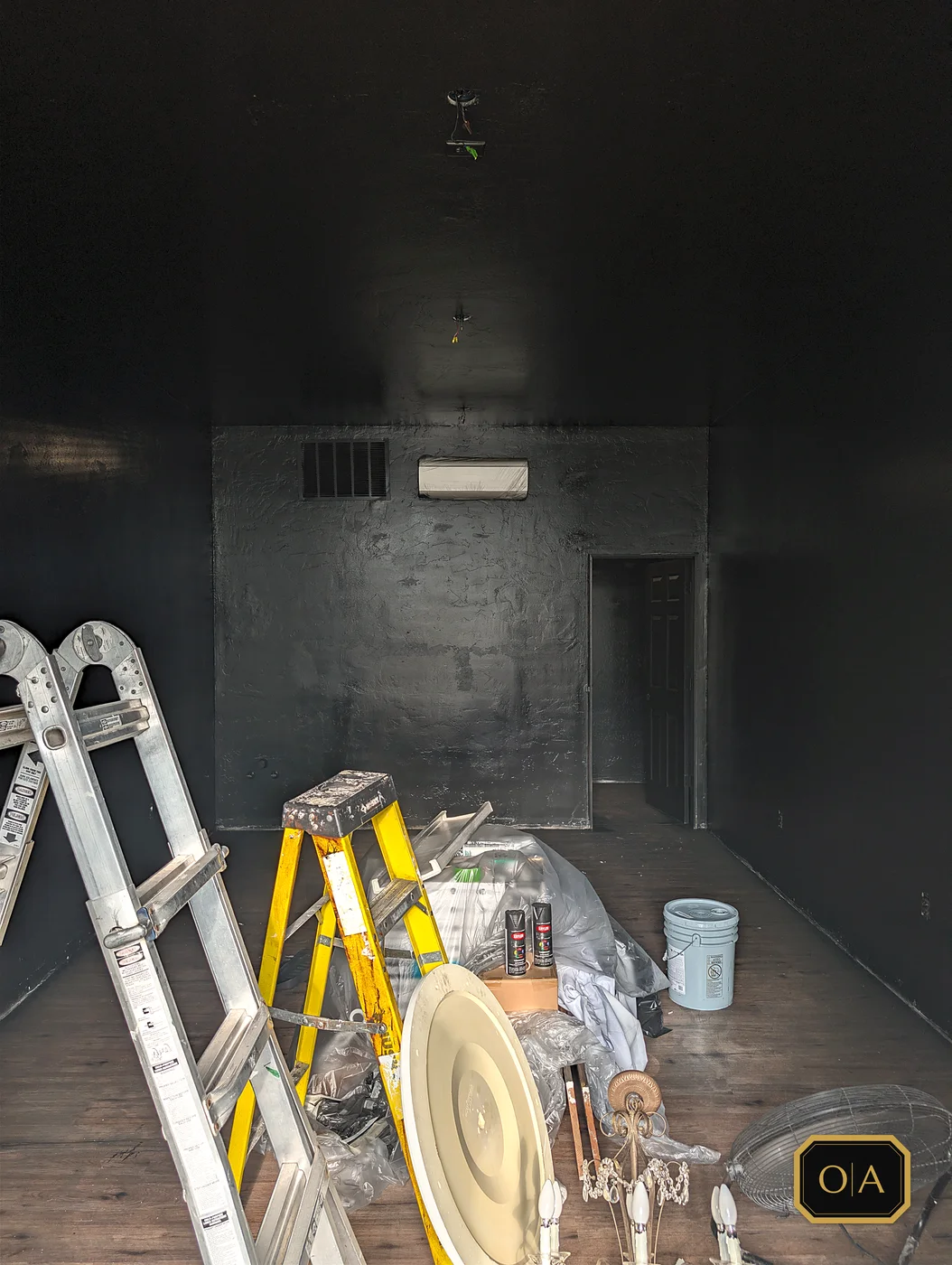The room painted black, with the trim stripped, the light fixtures down and the tools still in it.